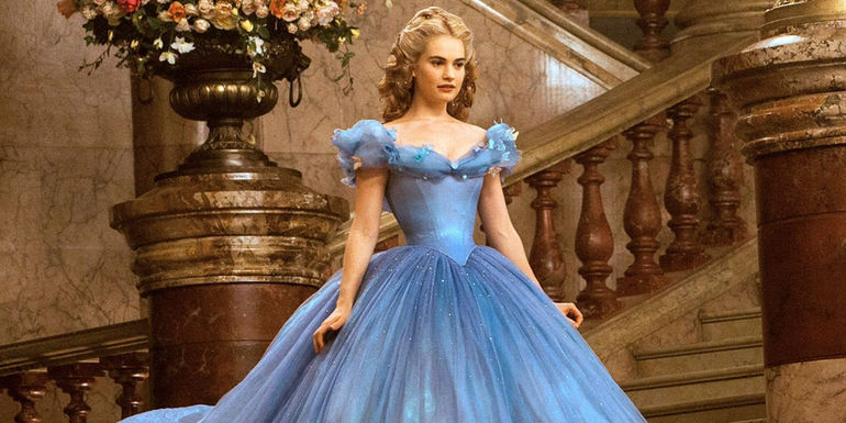 Lilly James as Cinderella standing in a blue flowing dress in Cinderella.