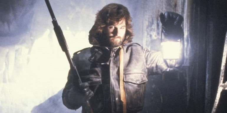 Kurt Russell holding a lantern and shotgun in The Thing