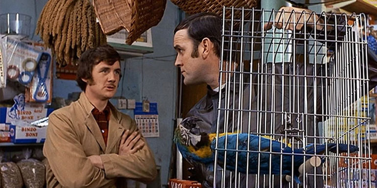 Michael Palin and John Cleese talking to each other while Cleese holds a Dead Parrot.