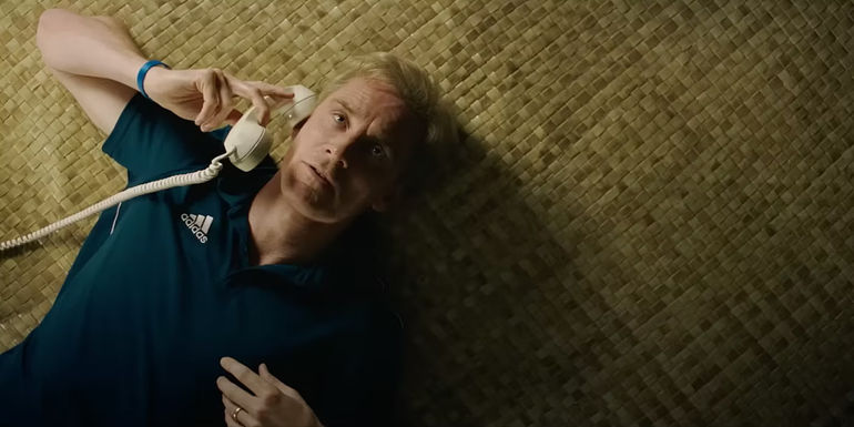 Michael Fassbender talks on the phone while lying on the floor in Next Goal Wins