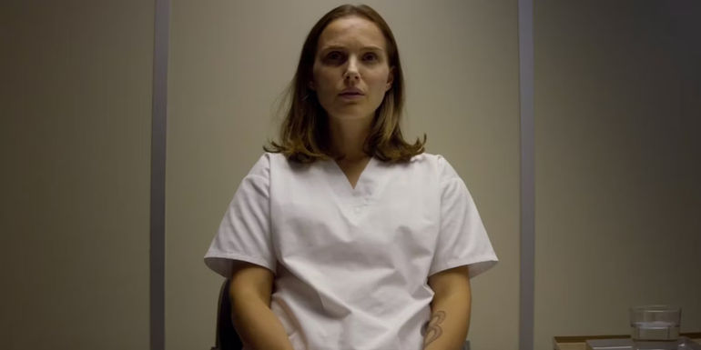 Lena sits in a chair with an ouroboros tattoo on her left arm in Annihilation.