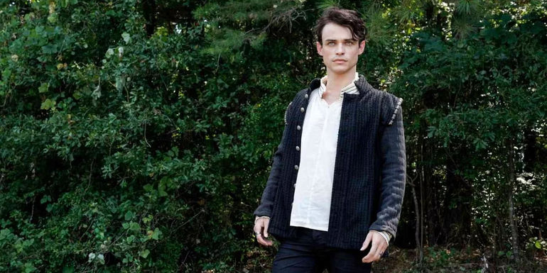 Sebastian (Thomas Doherty) standing in front of a bush in Legacies.