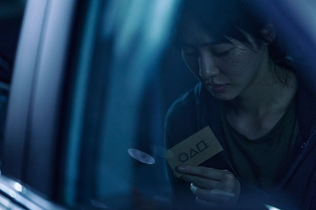 A female contestant in a car reading the invite in Squid Game season 2