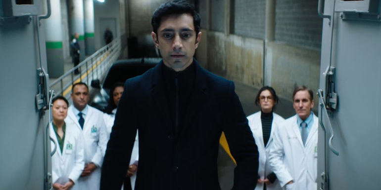 Riz Ahmed as Carlton Drake in Venom with lab workers behind him
