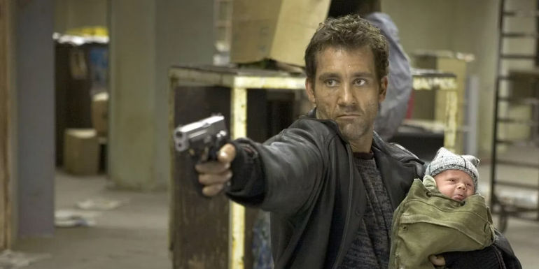 Clive Owen as Smith holding the baby and aiming a gun in Shoot 'Em Up