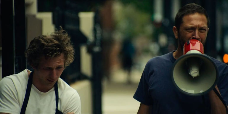 Carmy standing next to Richie who speaks into a blowhorn in The Bear