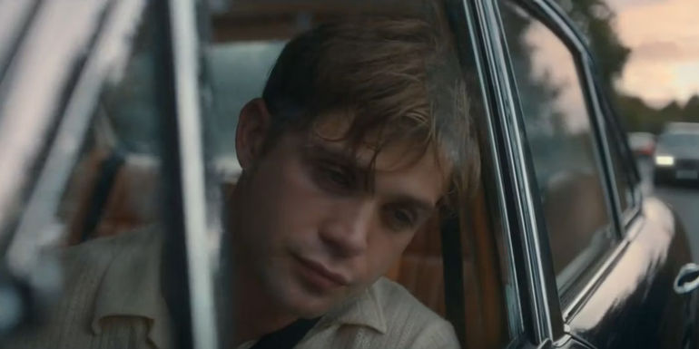 Dexter hangs his head out the window of a car in One Day