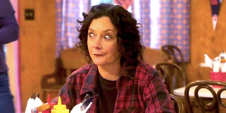 Sara Gilbert's Darlene pulls a face while sitting at a table in The Lunchbox in The Conners season 6 episode 2 - The Conners Revives a Forgotten Darlene Detail from the Past