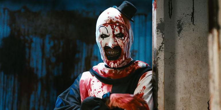 A bloody Art leans against a wall in Terrifier 2 - What Will Happen In The Next Terrifier Movie? - Terrifier 3 Story Details