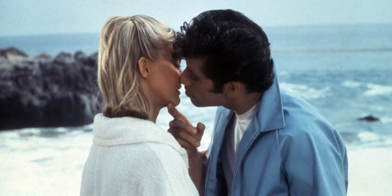 Danny trying to kiss Sandy on the beach in Grease