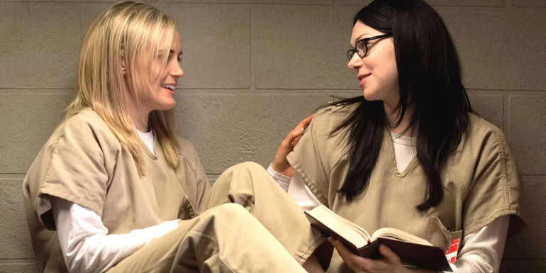 Piper and Alex sitting together in their cell with a book in Orange is the New Black