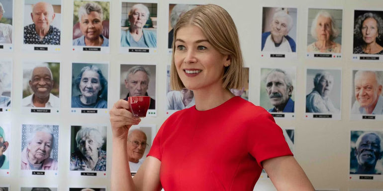 Rosamund Pike sips espresso while standing in front of a wall of potential victims in I Care A Lot