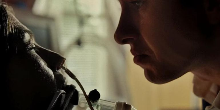 Oliver's face is inches from Elspeth's, who has a breathing tube in her nose and mouth in Saltburn.