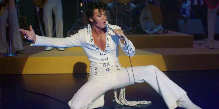 Austin Butler as Elvis Presley performing onstage in a white suit in Elvis (2022).