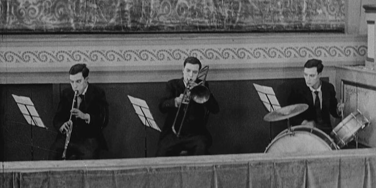 Three Buster Keatons playing instruments in The Playhouse.