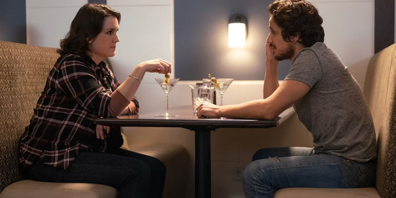 Shauna (Melanie Lynskey) and Adam (Peter Gadiot) sitting at a restaurant table in Yellowjackets