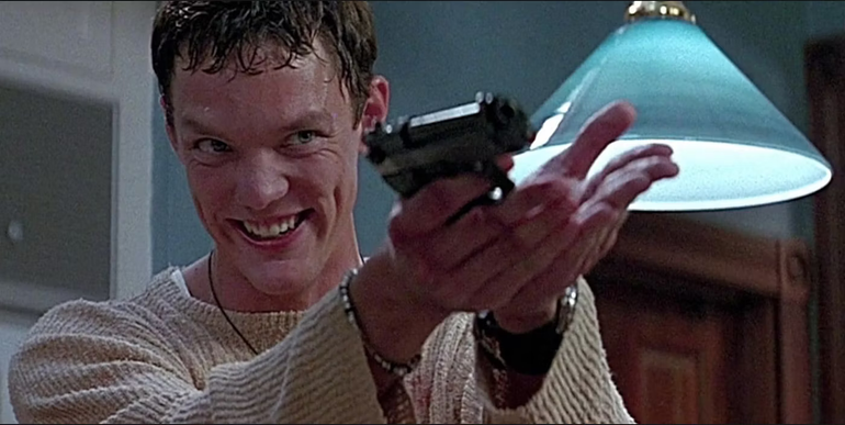 Stu (Matthew Lillard) holding a gun and smiling maniacally in Scream.