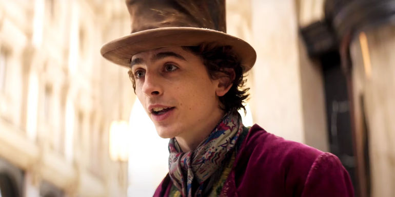 Timothee Chalamet dressed as Wonka with the tall hat and purple coat in Wonka movie