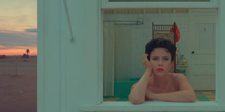 Scarlett Johansson as Midge Campbell leaning on a windowsill in Asteroid City