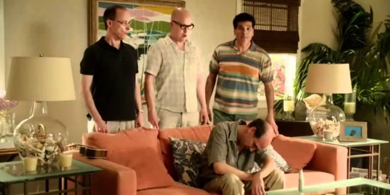 Sam Lloyd as Ted Buckland sitting on a couch with his band behind him in Cougar Town