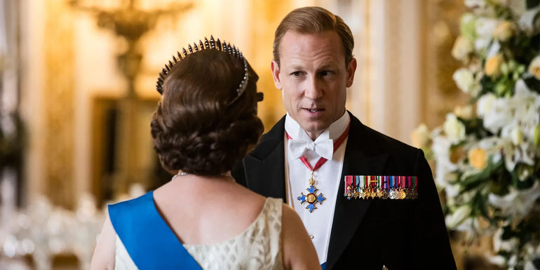 The Crown: Prince Philip (Tobias Menzies) in ceremonial uniform speaking to Queen Elizabeth (Olivia Colman), whose back is turned to the camera