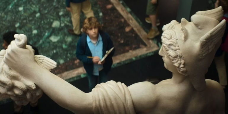 Walker Scobell as Percy Jackson looking up at a statue of Perseus in Percy Jackson & the Olympians