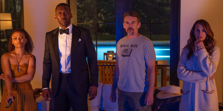 Myha'la, Mahershala Ali, Ethan Hawke, and Julia Robert looking worried as they stand in front of a TV screen in Leave the World Behind.