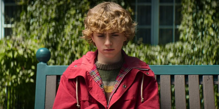 Walker Scobell as Percy Jackson sitting on a bench in Yancy Academy's garden in Percy Jackson & the Olympians