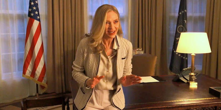 President Ellen (Uma Thurman) raising her hands and smiling in the Oval Office in Red, White and Royal Blue.