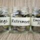 three jars of coins labels savings, retirement, emergency plan, for budgeting