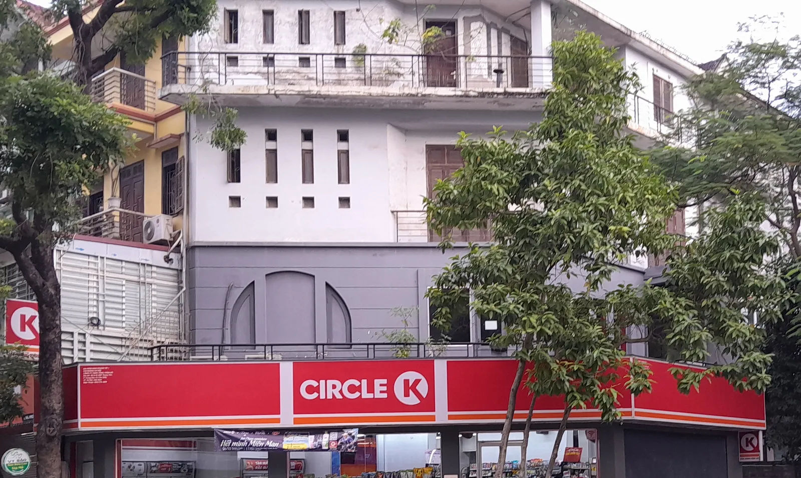 Mặt tiền một cửa hàng Circle K với dải biển đỏ và dãy kệ sáng đèn bên trong