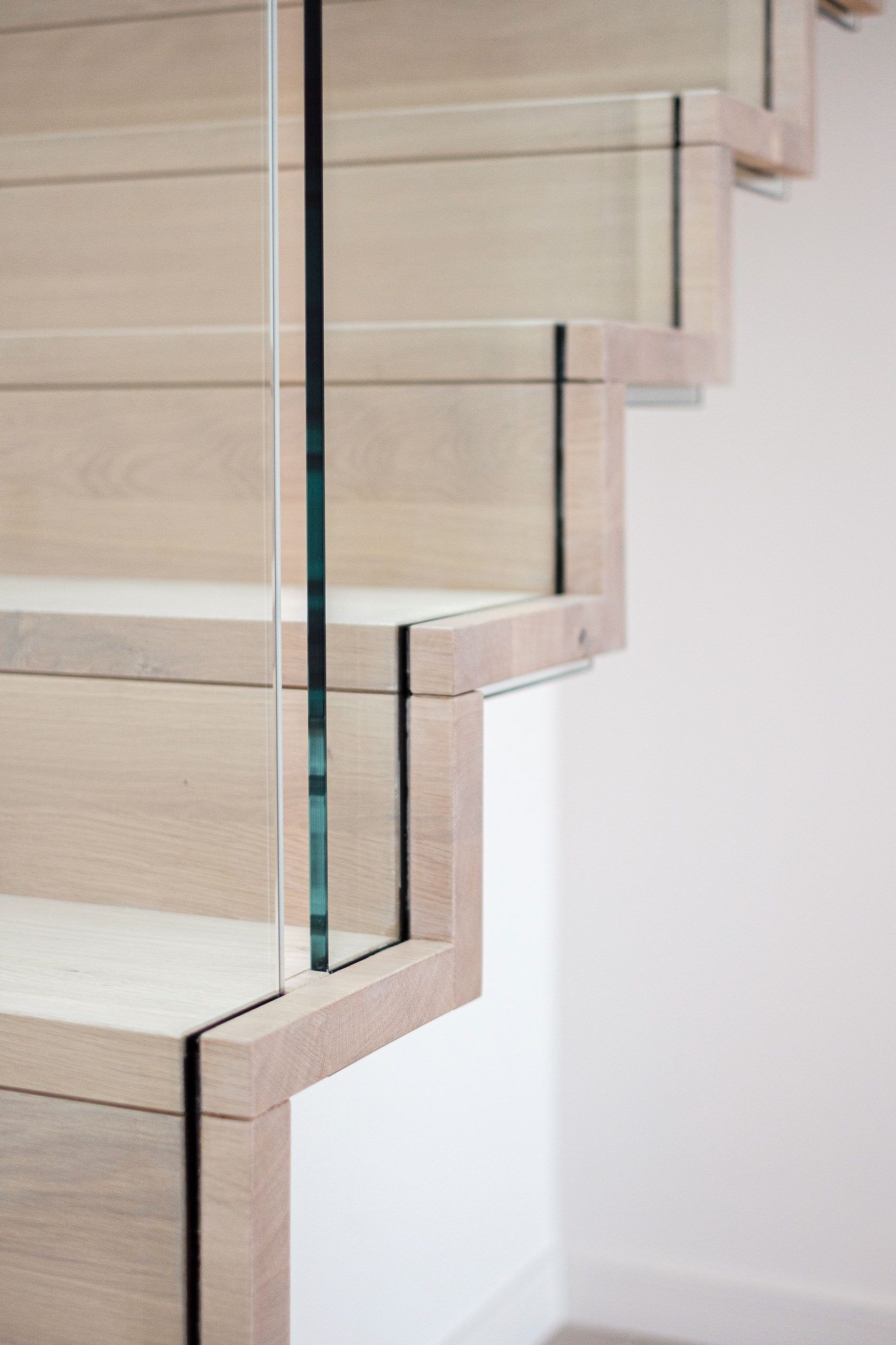 Side view of slim profile cantilevered oak staircase handrail and glass balustrade.