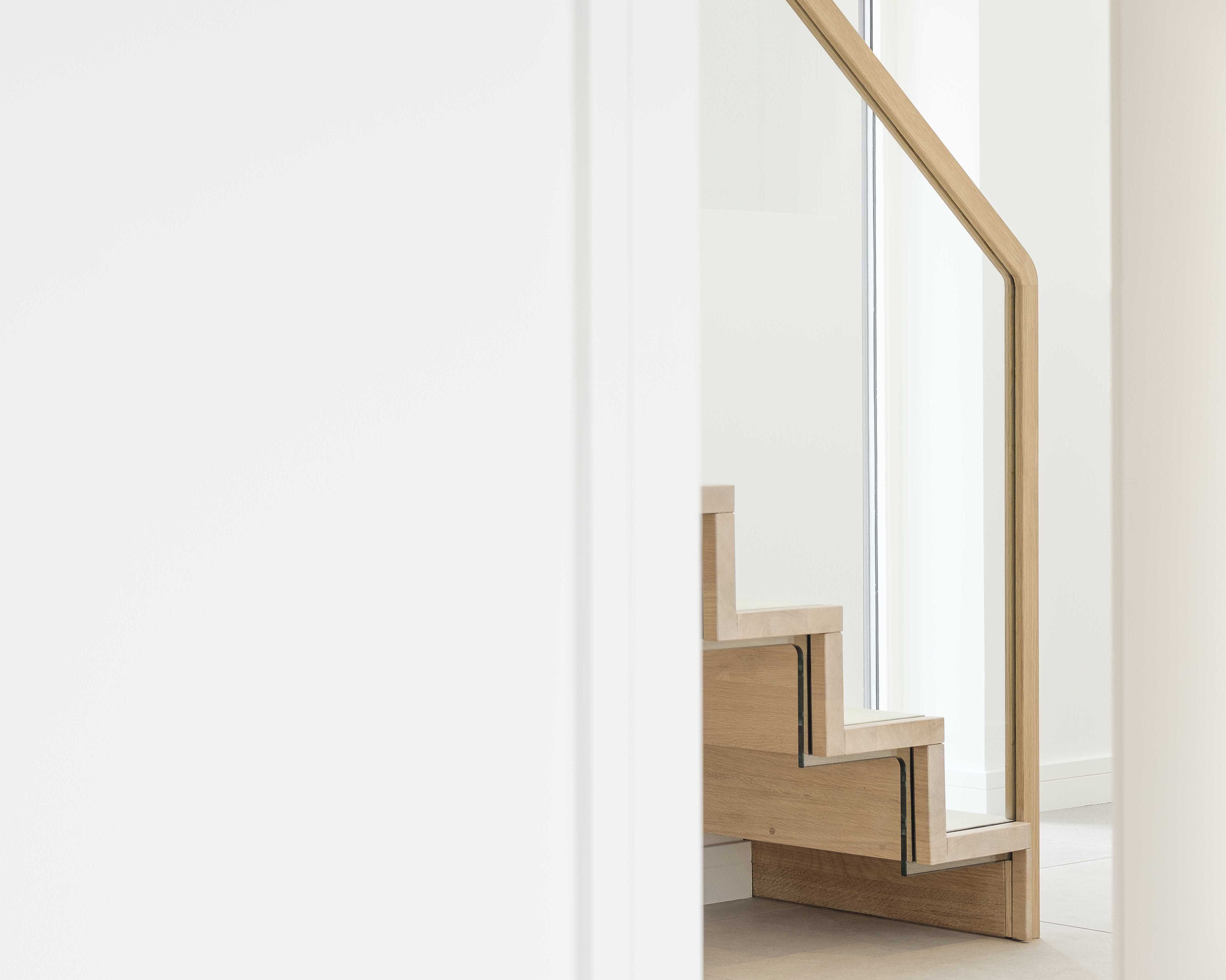 Side view of slim profile cantilevered oak staircase handrail and glass balustrade.