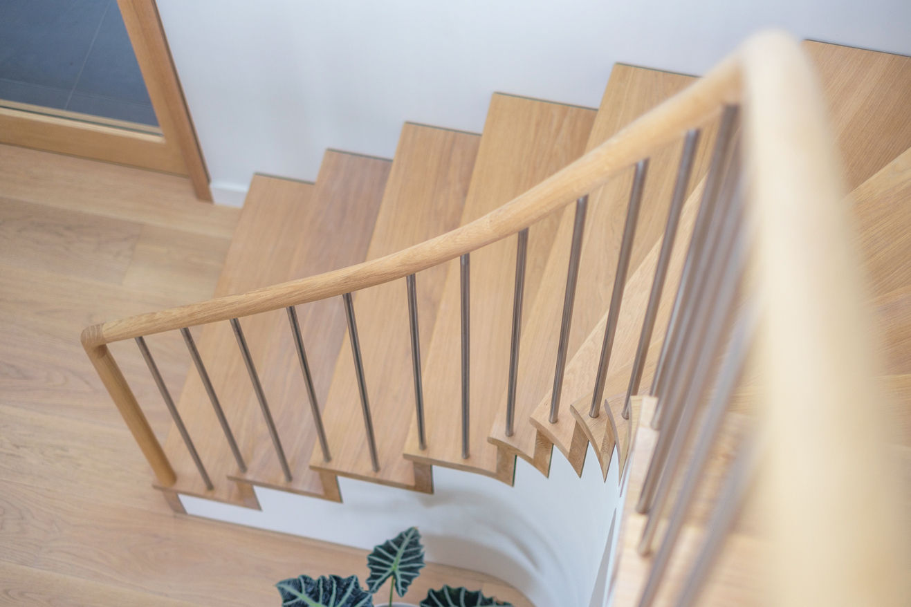 Soft focus oak staircase and oak handrail, with stainless steel spindles. Plant slightly out of shot.