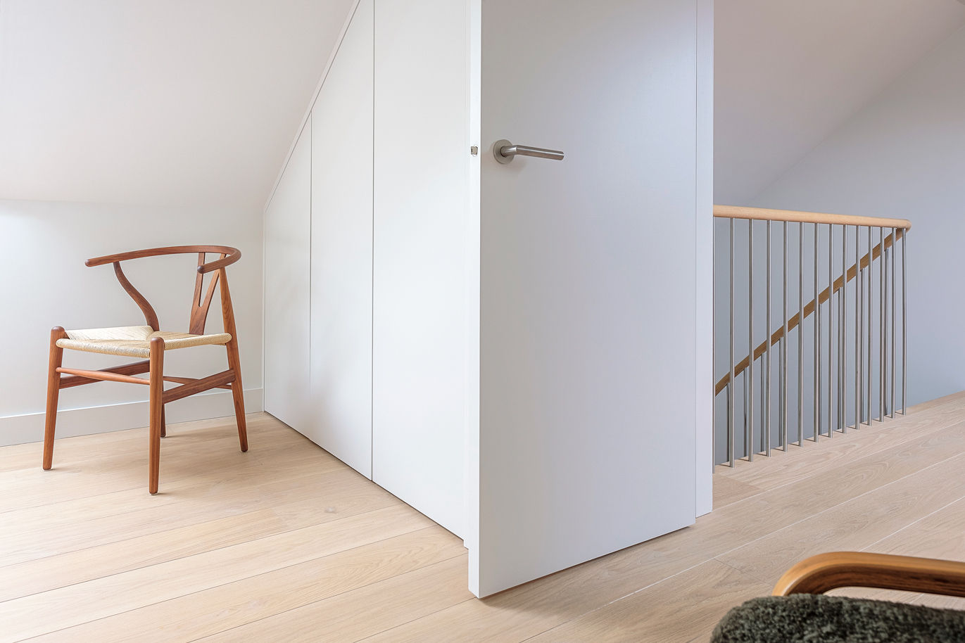 Classic domestic Oak interior with walnut Wishbone chair oak stair and handrail with white walls.