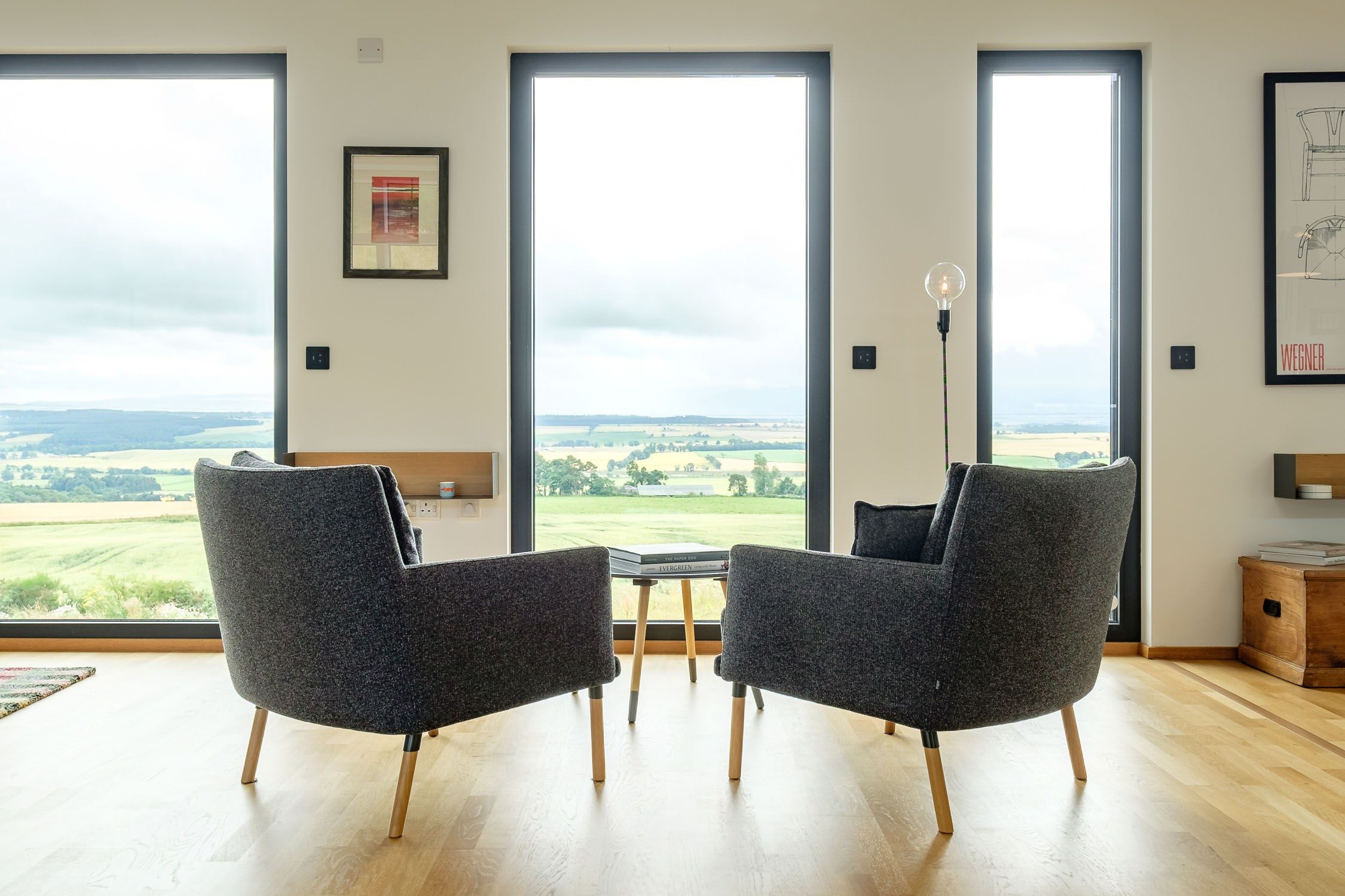 Two grey modular chairs facing window view of fields.