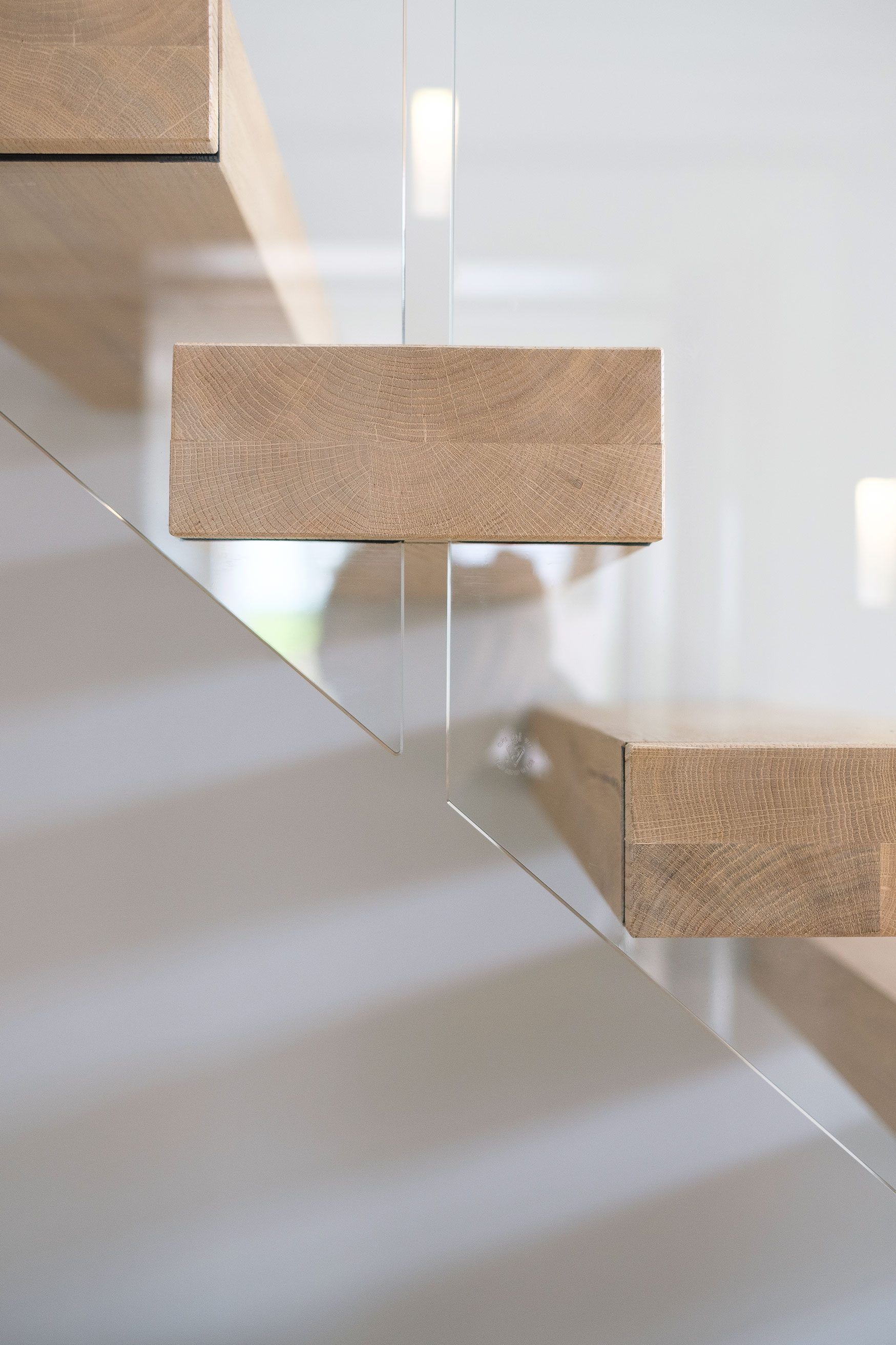 Side view of floating cantilevered oak stair treads showing end grain with glass balustrade.