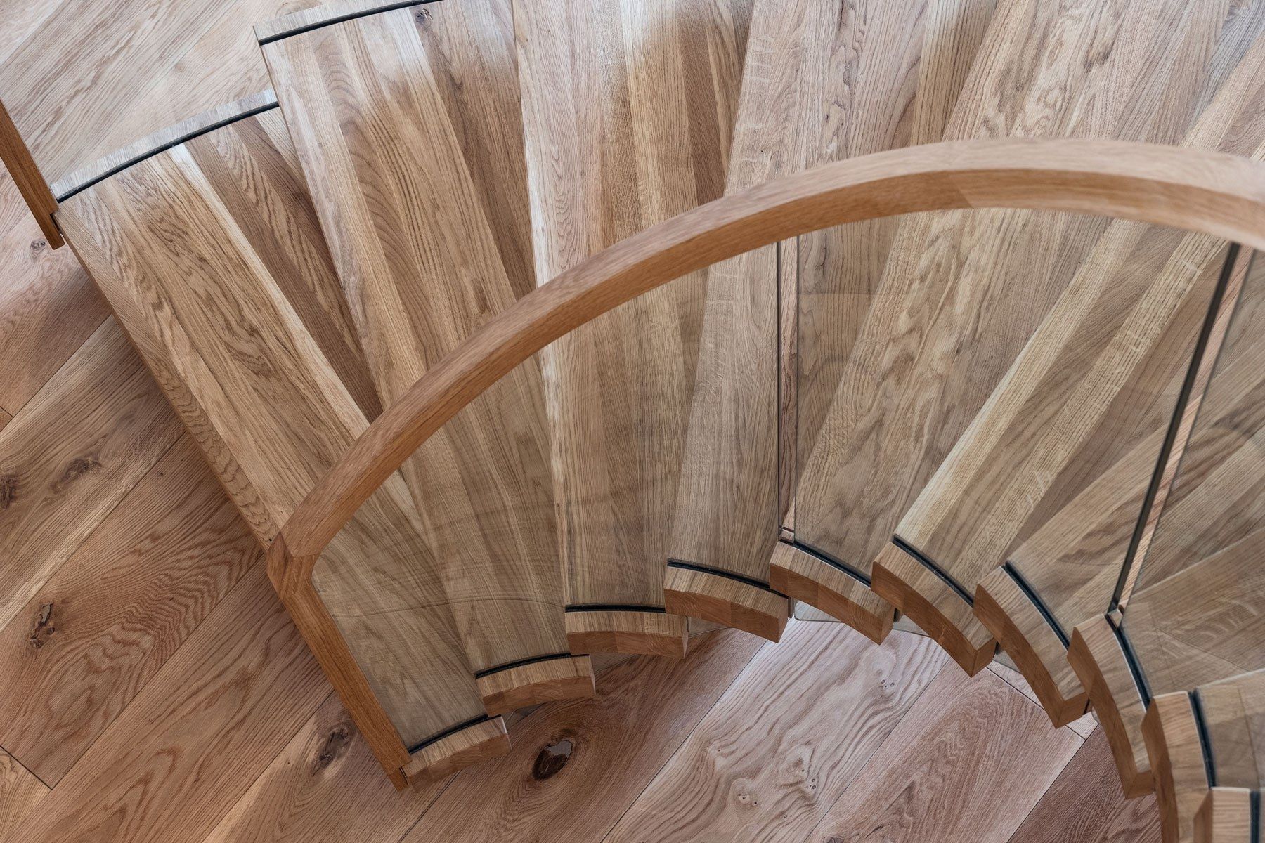 Birds eye view of feature curved oak stair centrepiece with curved glass and curved oak handrail.