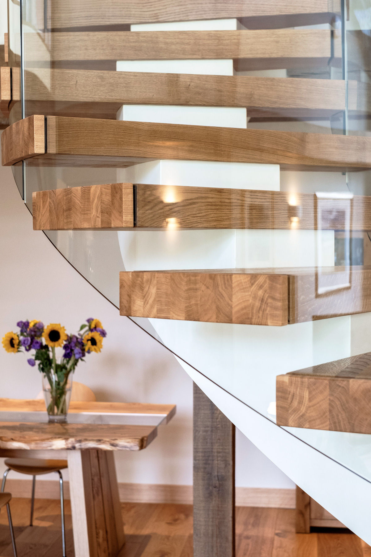 Side view of feature curved oak staircase centrepiece with curved glass in green oak framed home.