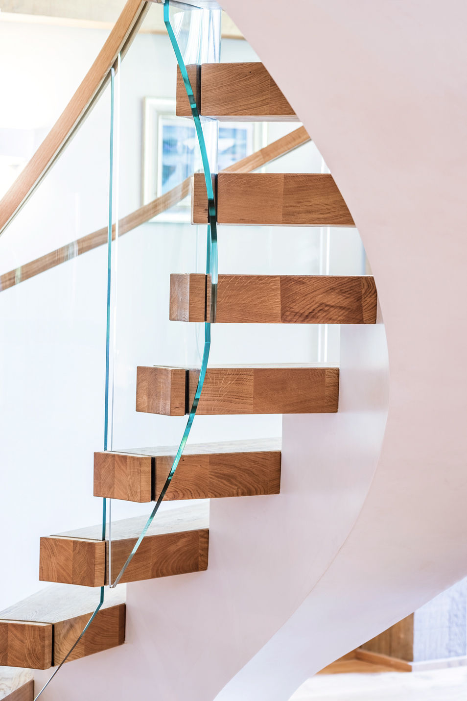 Underside of contemporary curved floating oak stair centrepiece with curved glass and curved oak handrail.