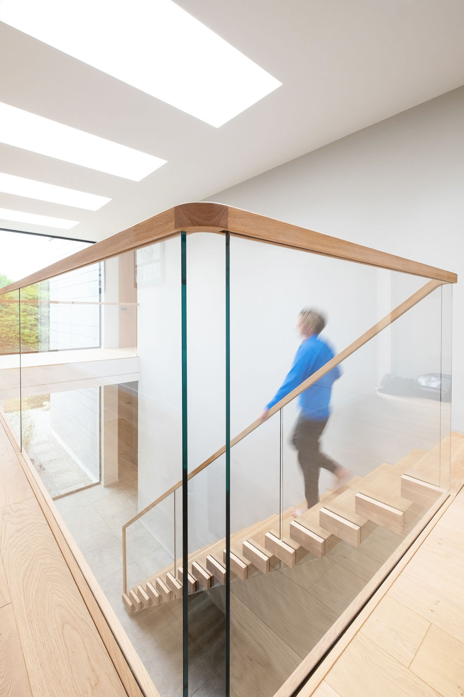 Man in blue jumper walking down cantilevered feature staircase.