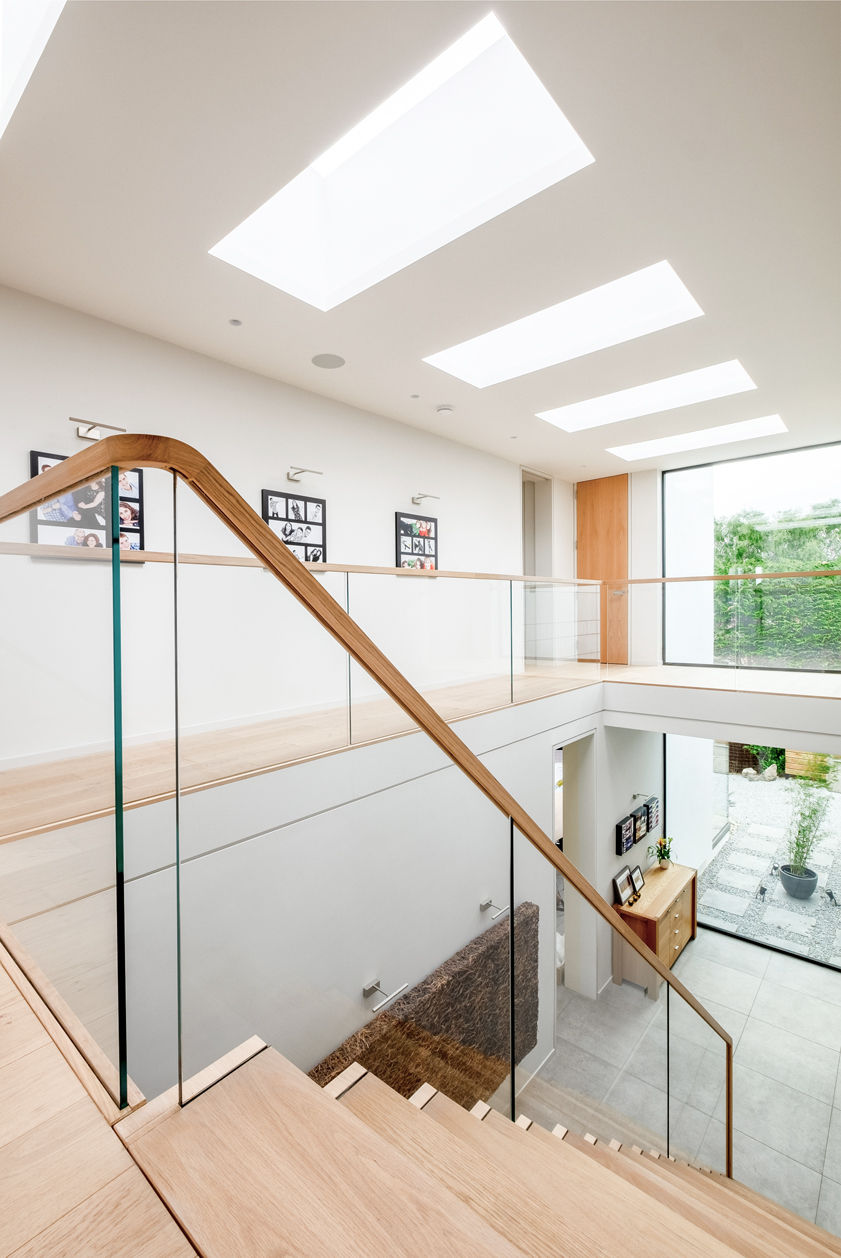 Cantilevered feature staircase with oak treads and glass balustrade from upper level.