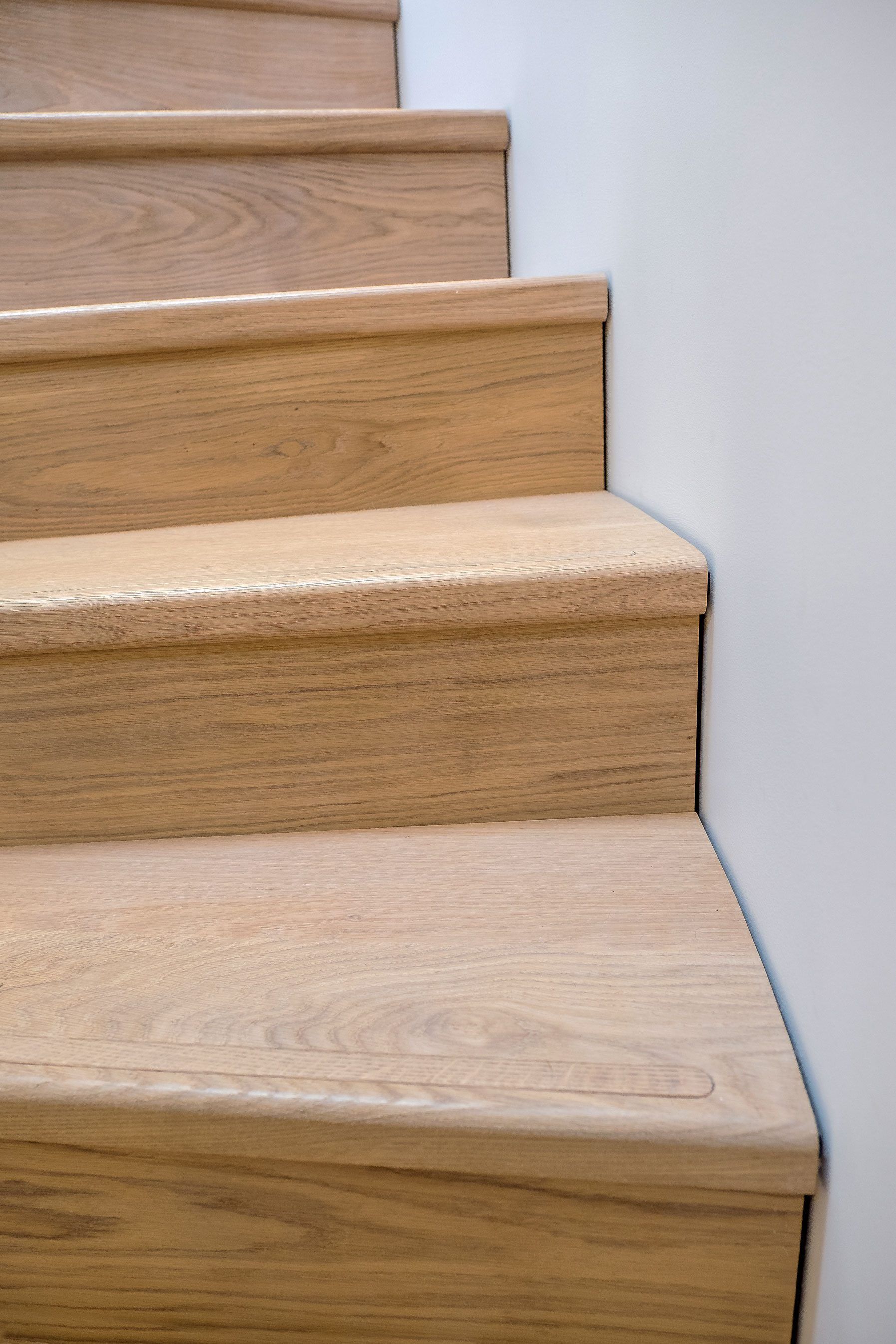 Oak stair treads and risers meeting a plastered wall and shadow gap detail.