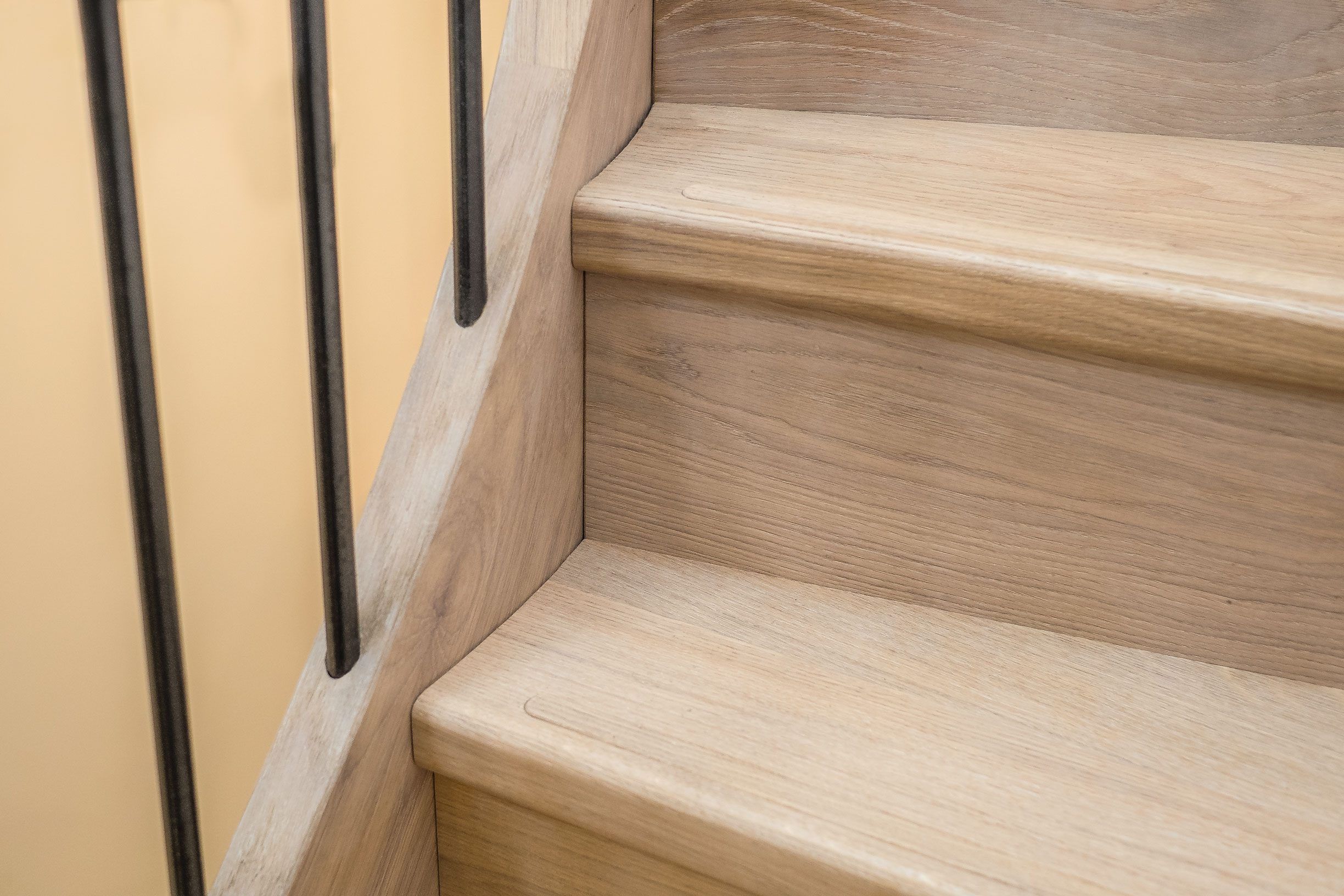 Close up of Oak elliptical stair treads with iron balustrade and oak stringer.