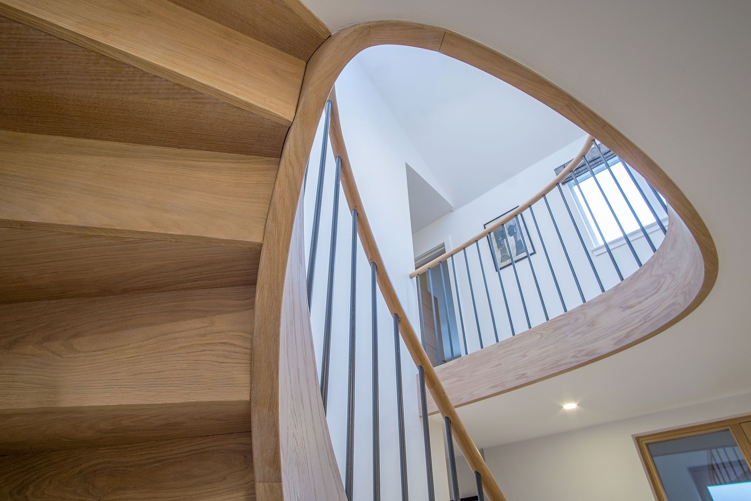 Underside view of feature Elliptical oak stair with iron balustrade and oak handrail.