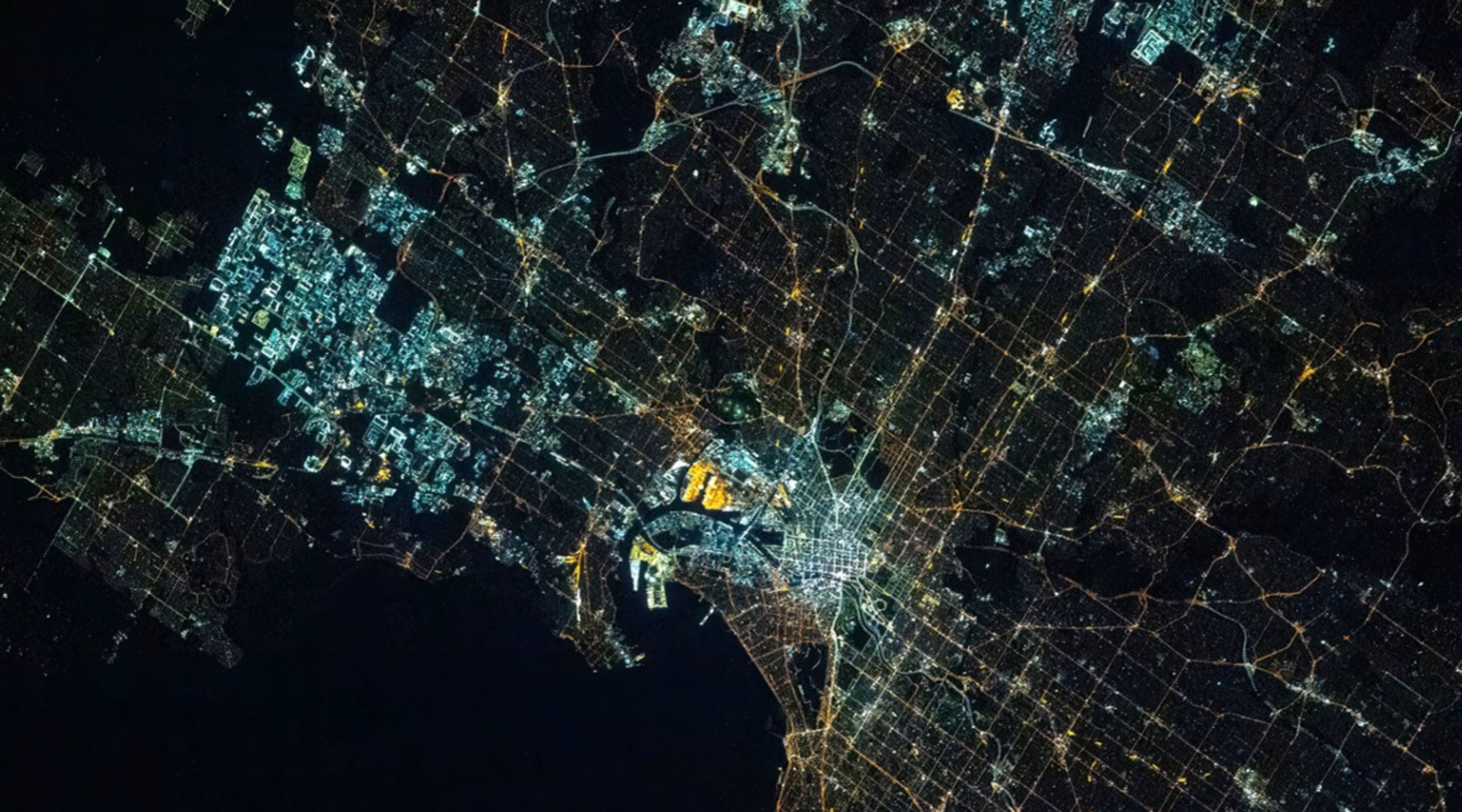 A city at night in colour, cool white lit districts sitting directly against warm amber ones.