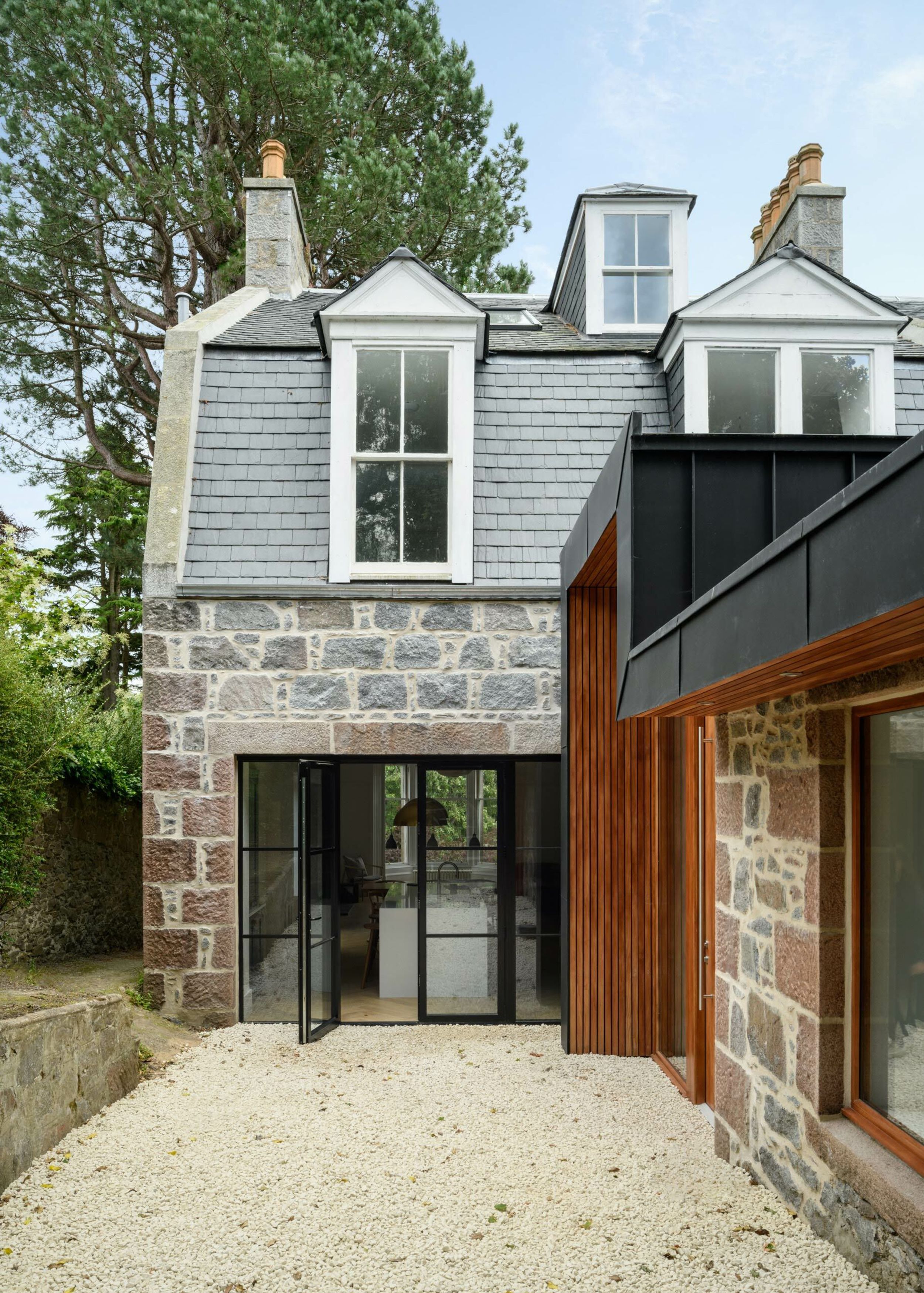 Two and a half story Victorian house with Crittal style doors and timber and black zinc extension entrance canopy