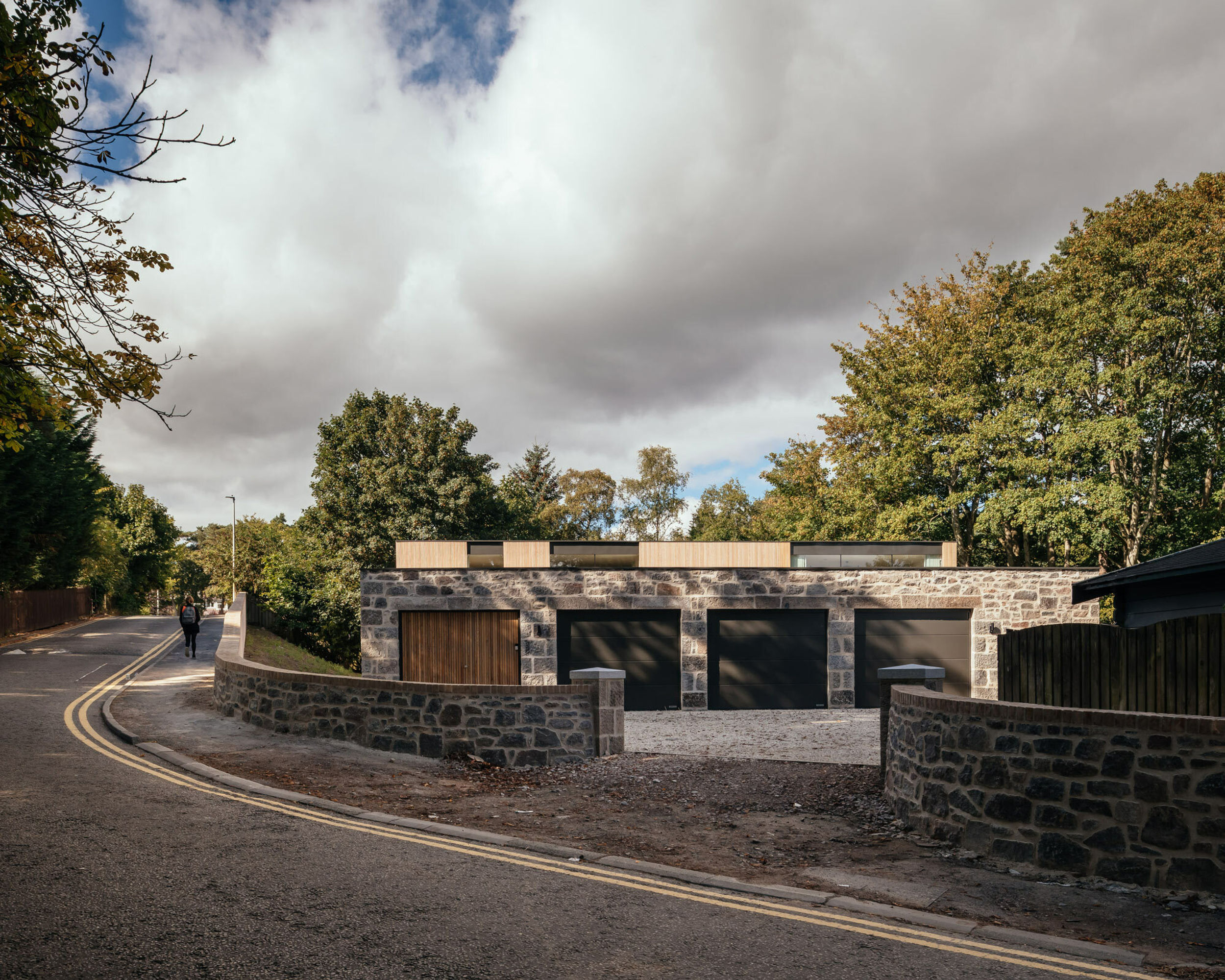 A three car garage made of stone. A granite stone boundary wall at the entrance.