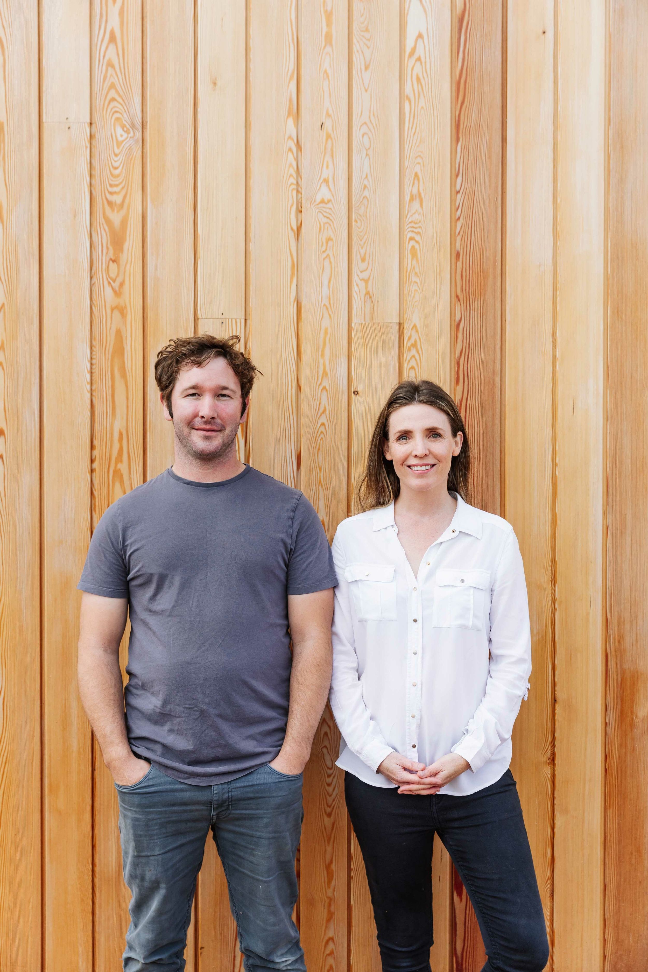 A man in a blue shirt and a woman in a white shirt stand together in front of a timber larch cladding.