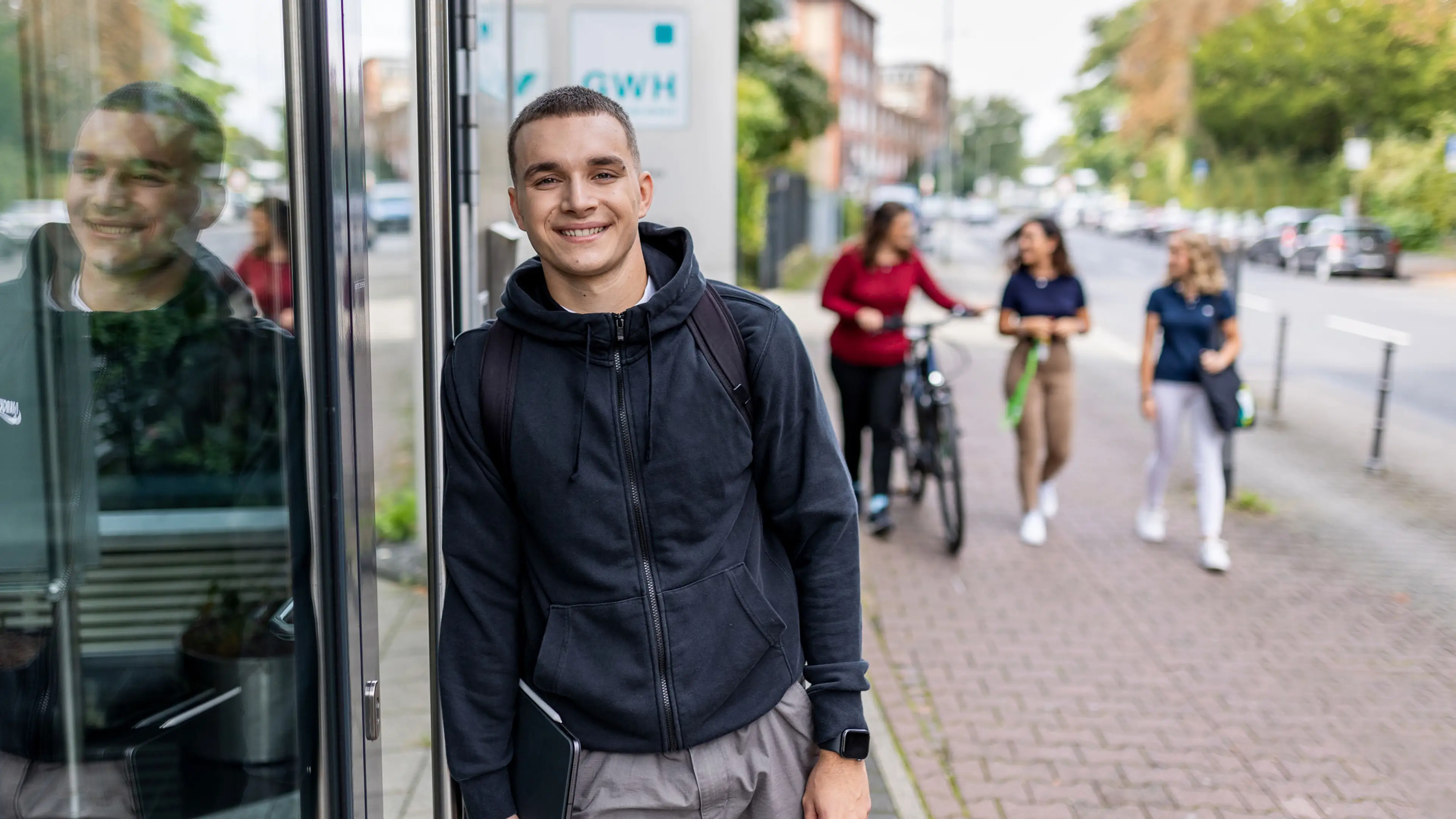 Auszubildender steht vorm Haupteingang der GWH in Frankfurt